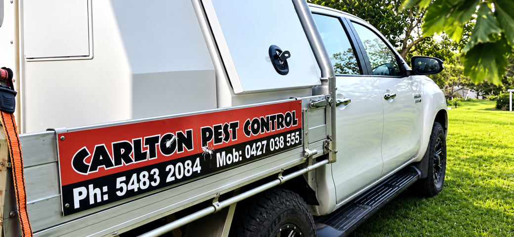 The Carlton Pest Control vehicle, branded with the business's phone number, parked on a grassed property